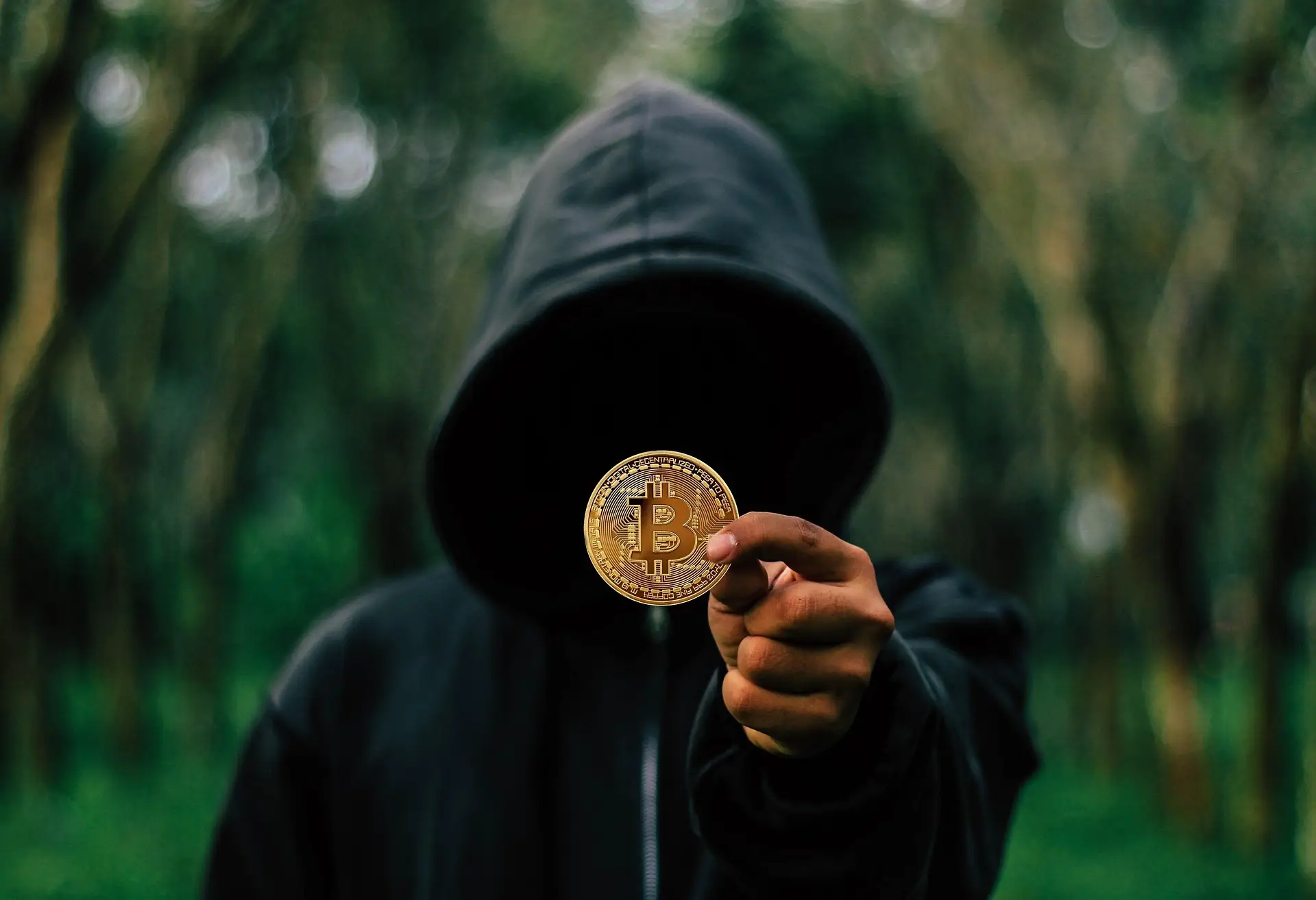 Persona incappucciata con una moneta bitcoin