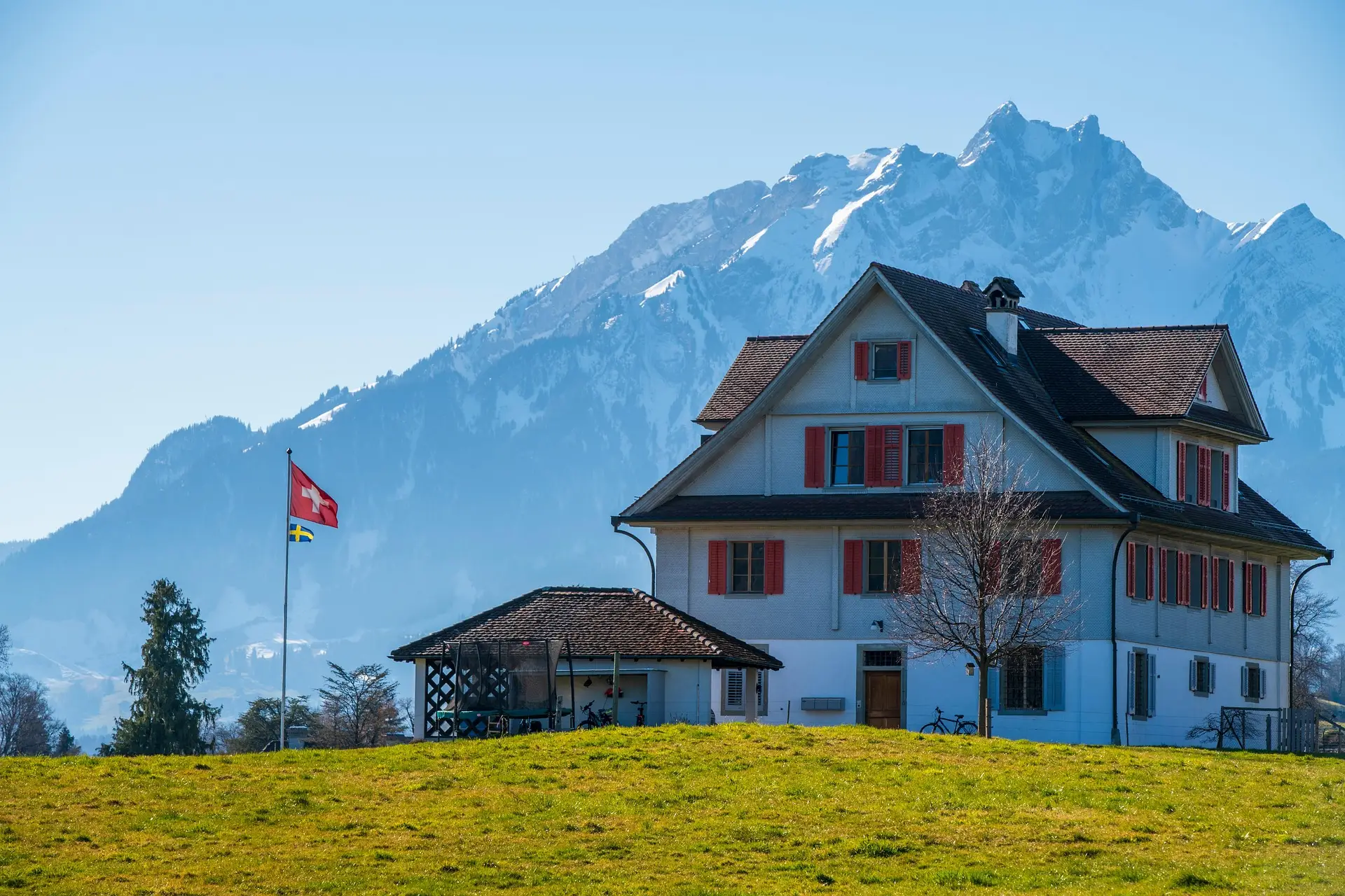 Schweizer Bauernhaus mit Flagge vor den Alpen
